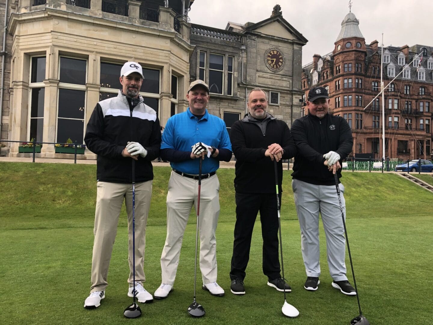 Four men are standing on a golf course.