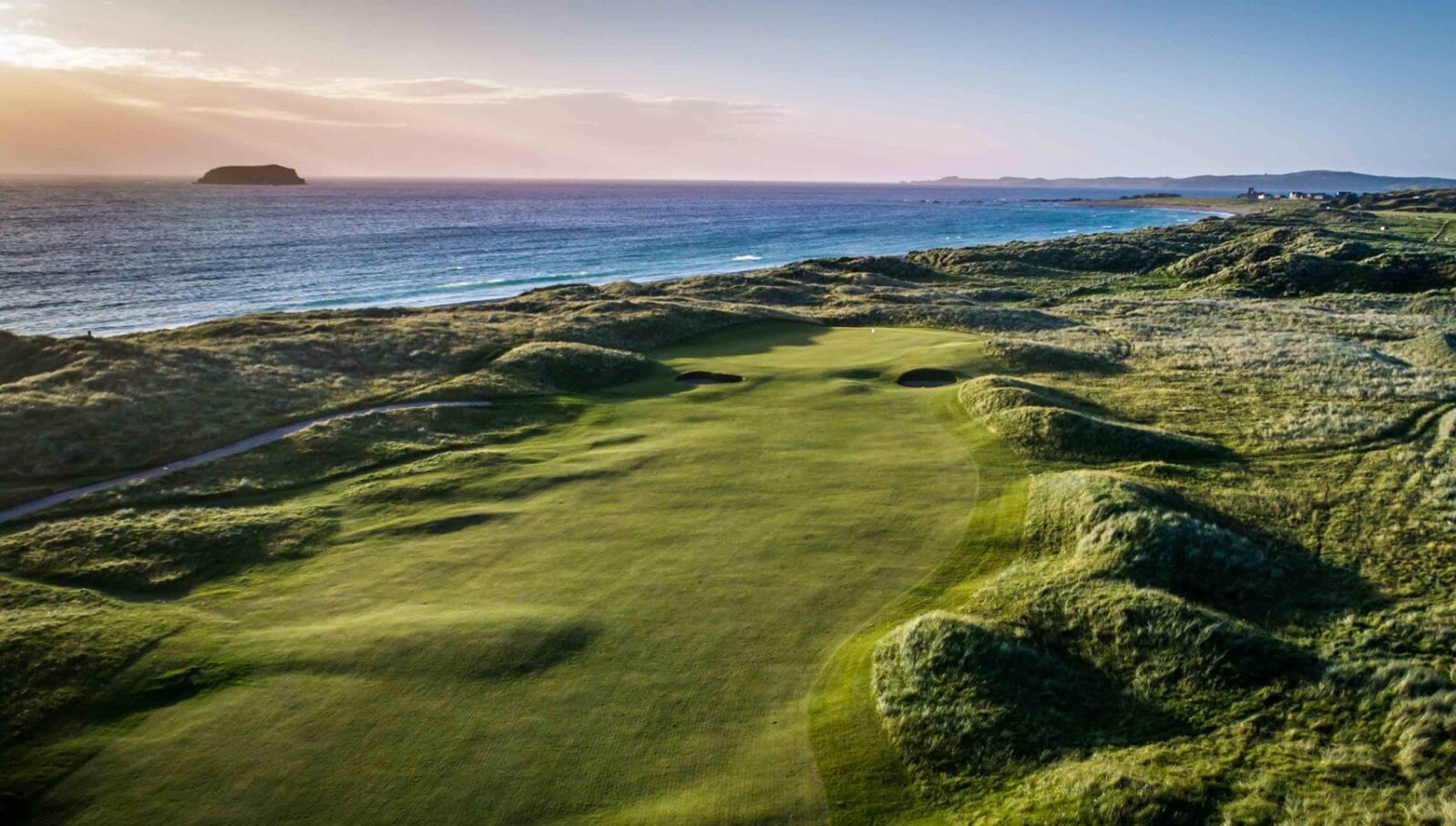 A view of the ocean from above on a golf course.