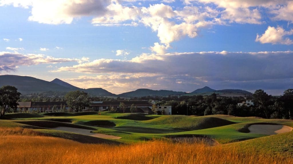 A view of a golf course with mountains in the background.