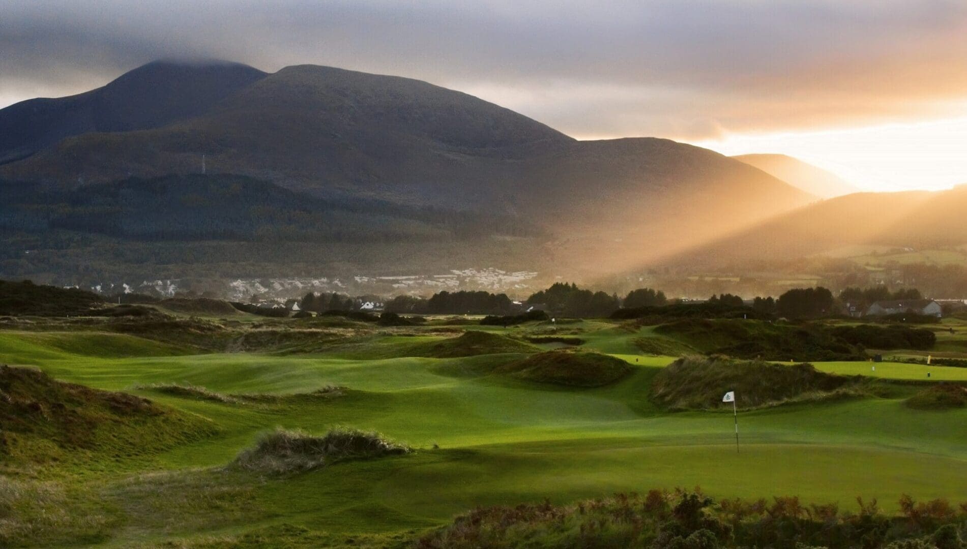 A view of the sun setting over a golf course.