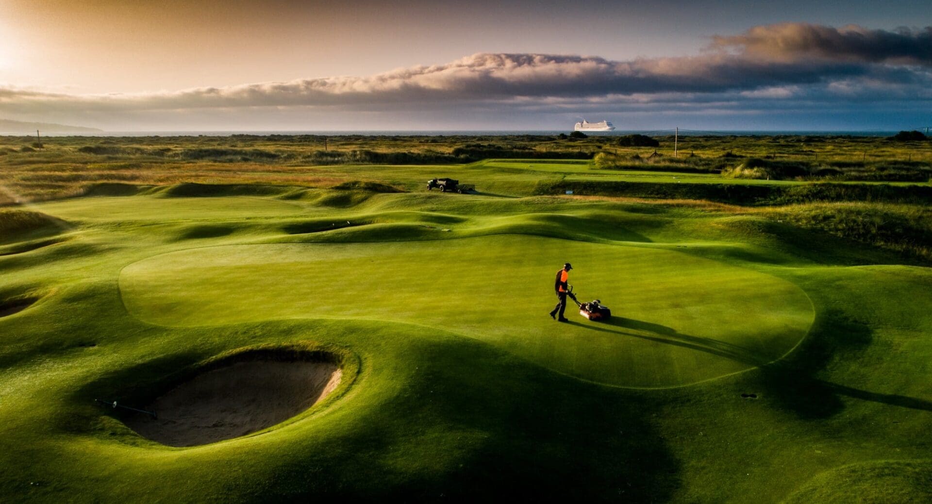 A person is walking across the grass on a golf course.