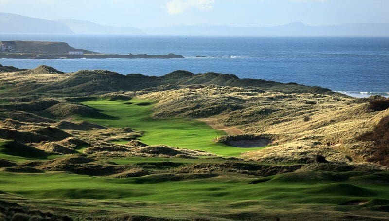 A view of the ocean from above a golf course.