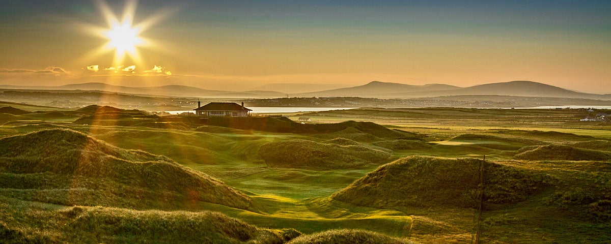 A view of a golf course with mountains in the background.