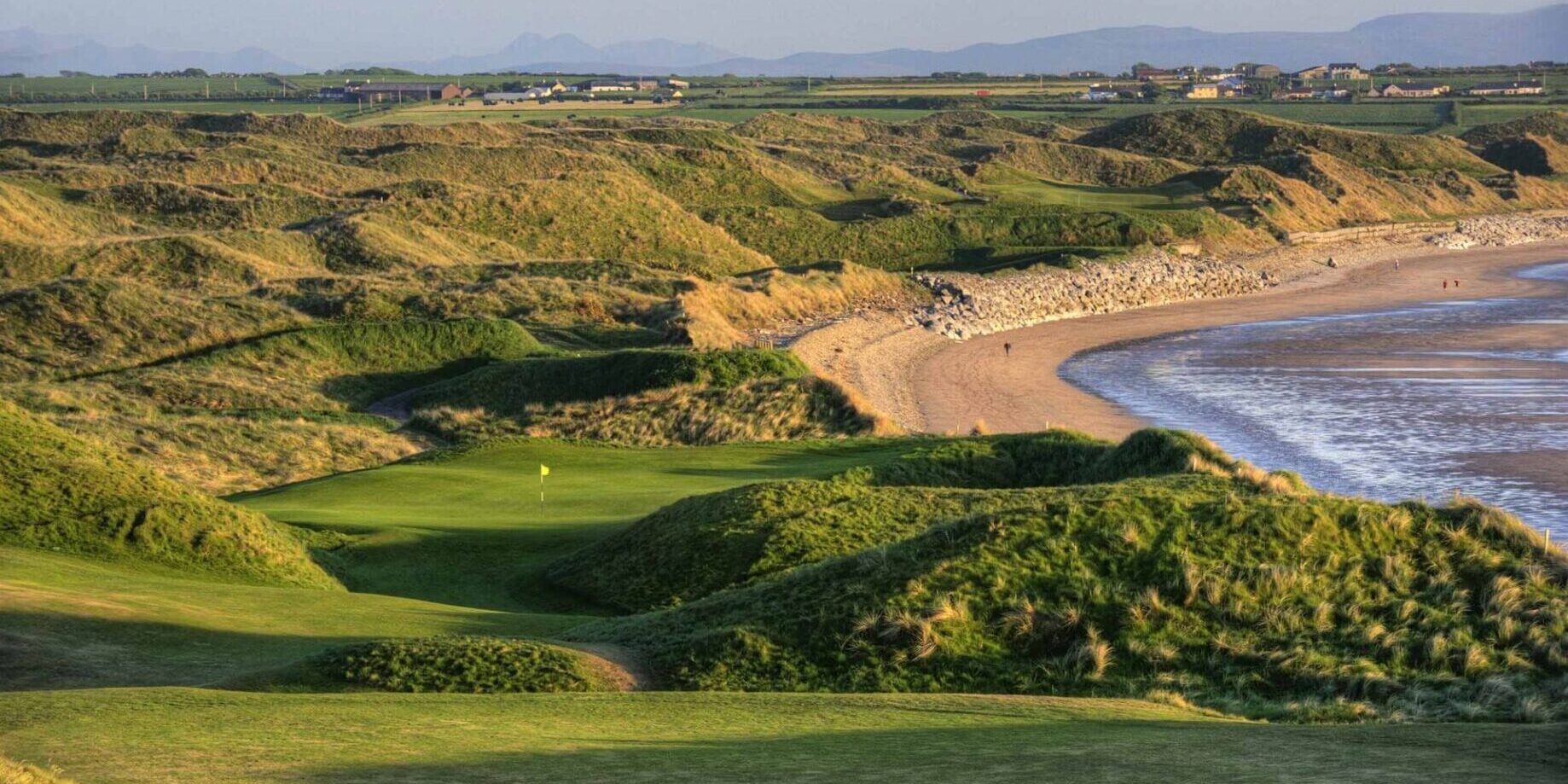 A view of the ocean from above, with a golf course in the foreground.