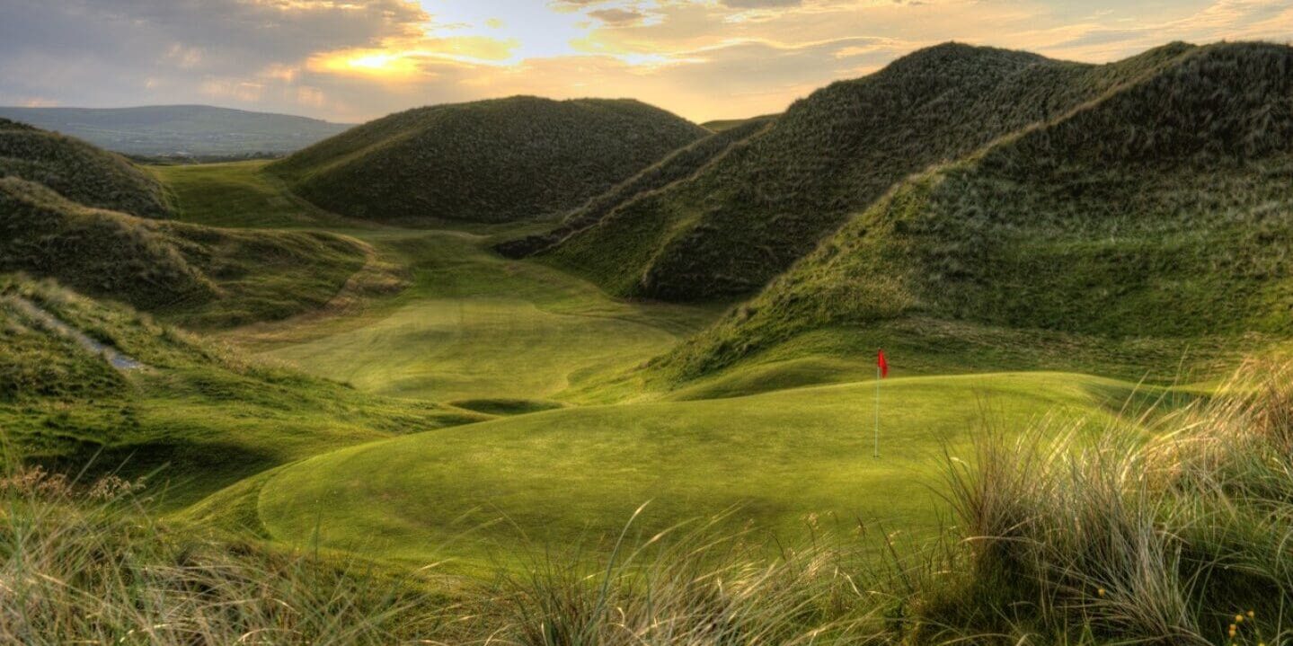 A view of a golf course with mountains in the background.